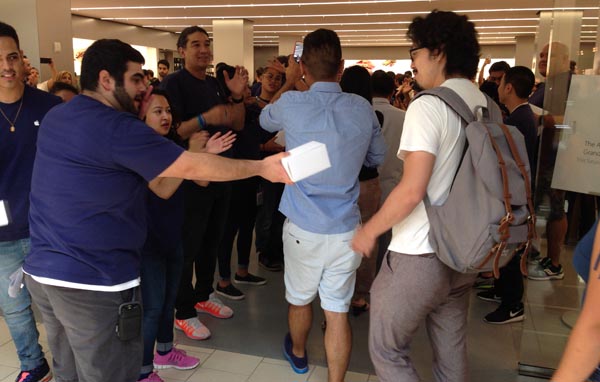 Empleados de la tienda Apple entregando camisetas a los clientes en señal de agradecimiento.