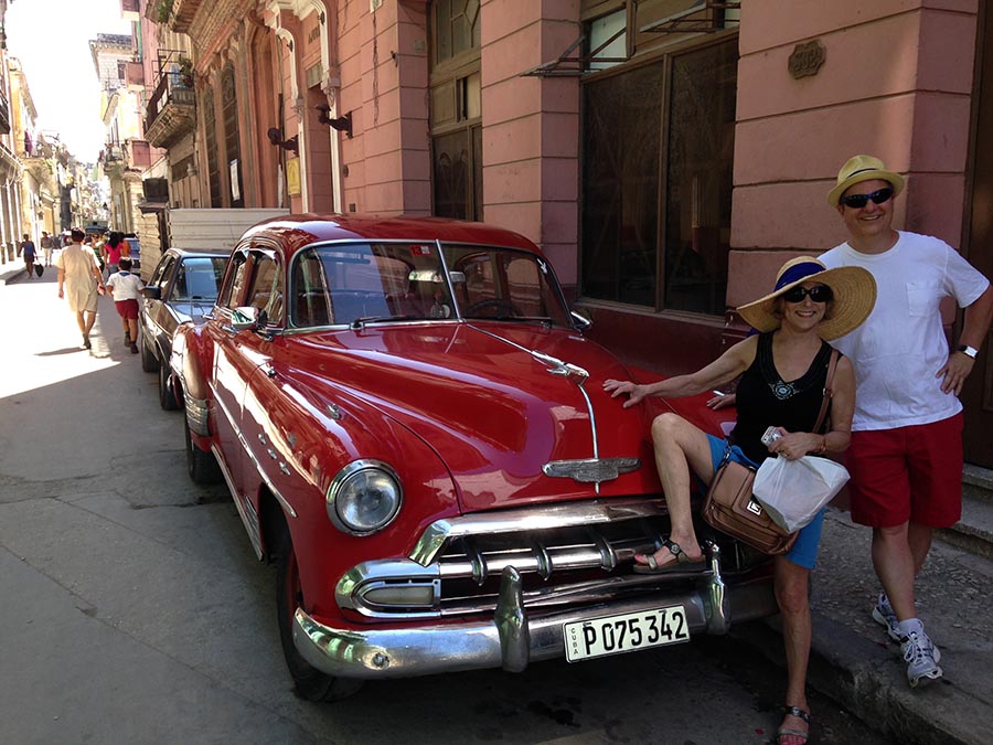 Los turistas posan fascinados al lado de los carros clásicos en La Habana. Foto Roger Rivero